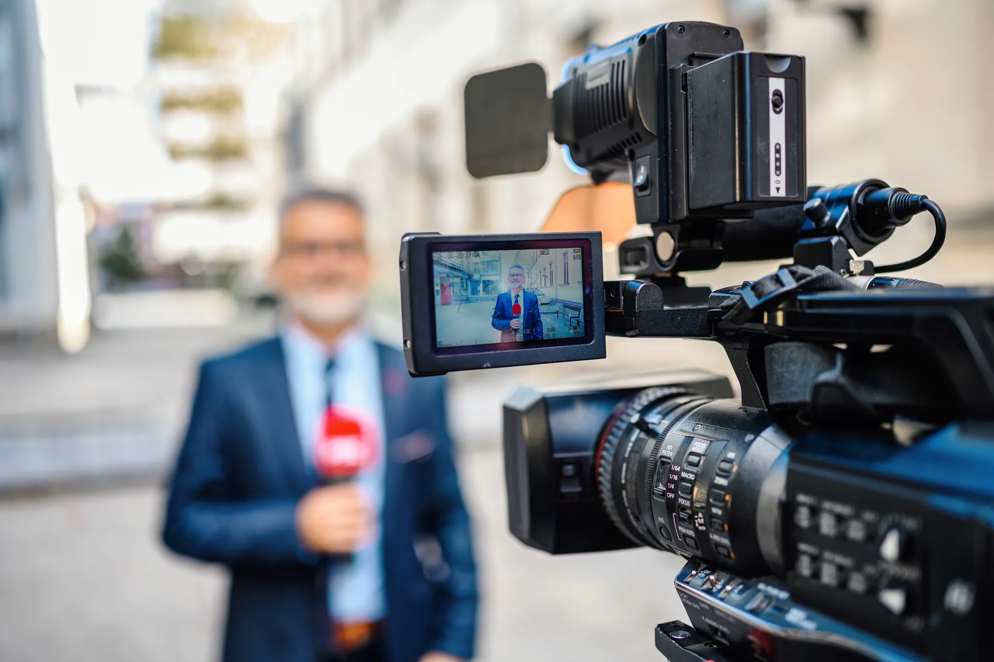 TV-kamera filmar reporter under intervju i stadsmiljö – illustration av media och
reportage.