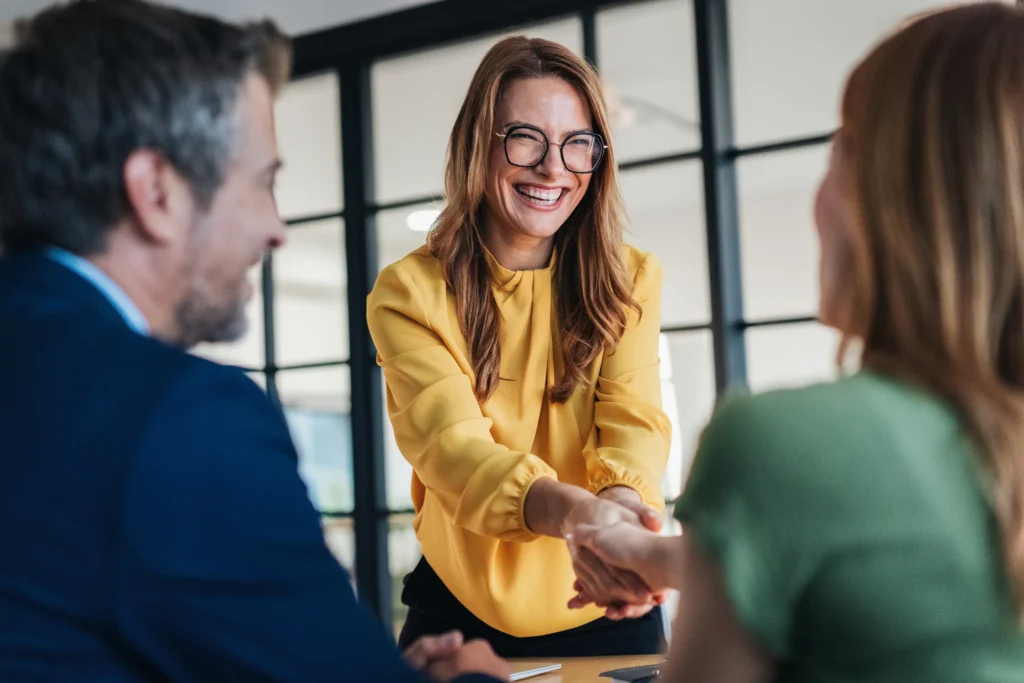 Leende affärspersoner i möte som tar i hand – symbol för professionell relation, förtroende och affärsutveckling inom säljteknik för Key Account Managers.