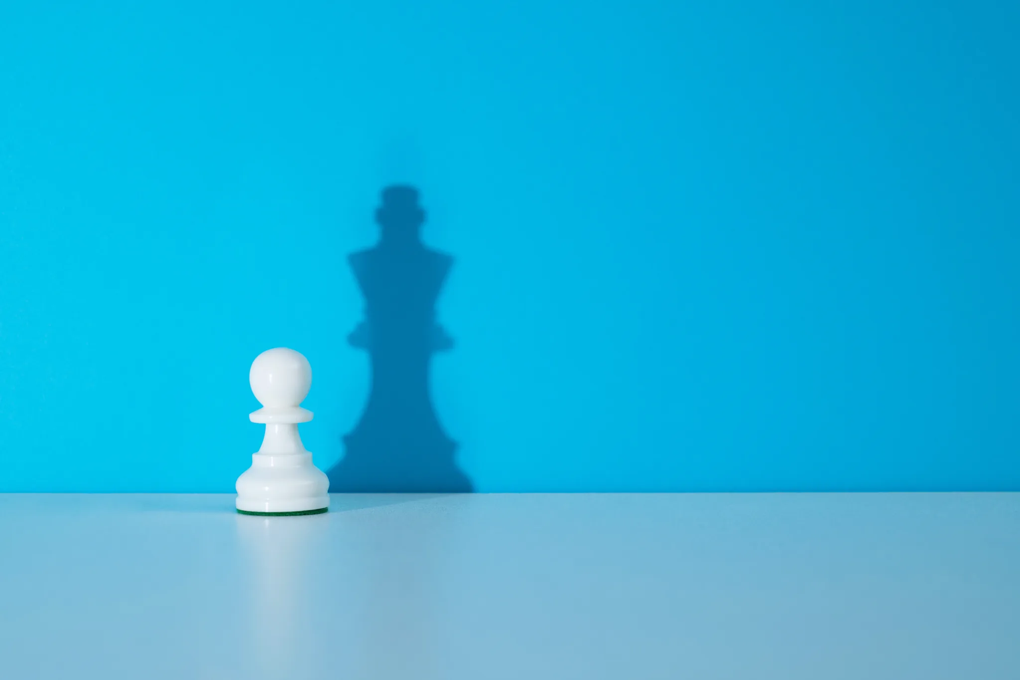 Vit schackpjäs med skugga av kung som symbol för strategisk rådgivning inom förhandling och sälj.