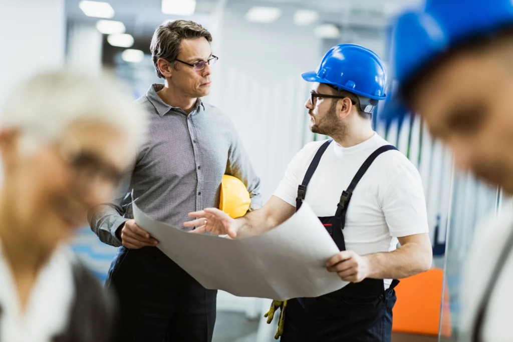 Medarbetare i industriell miljö diskuterar ritning som del av förhandlingsträning.