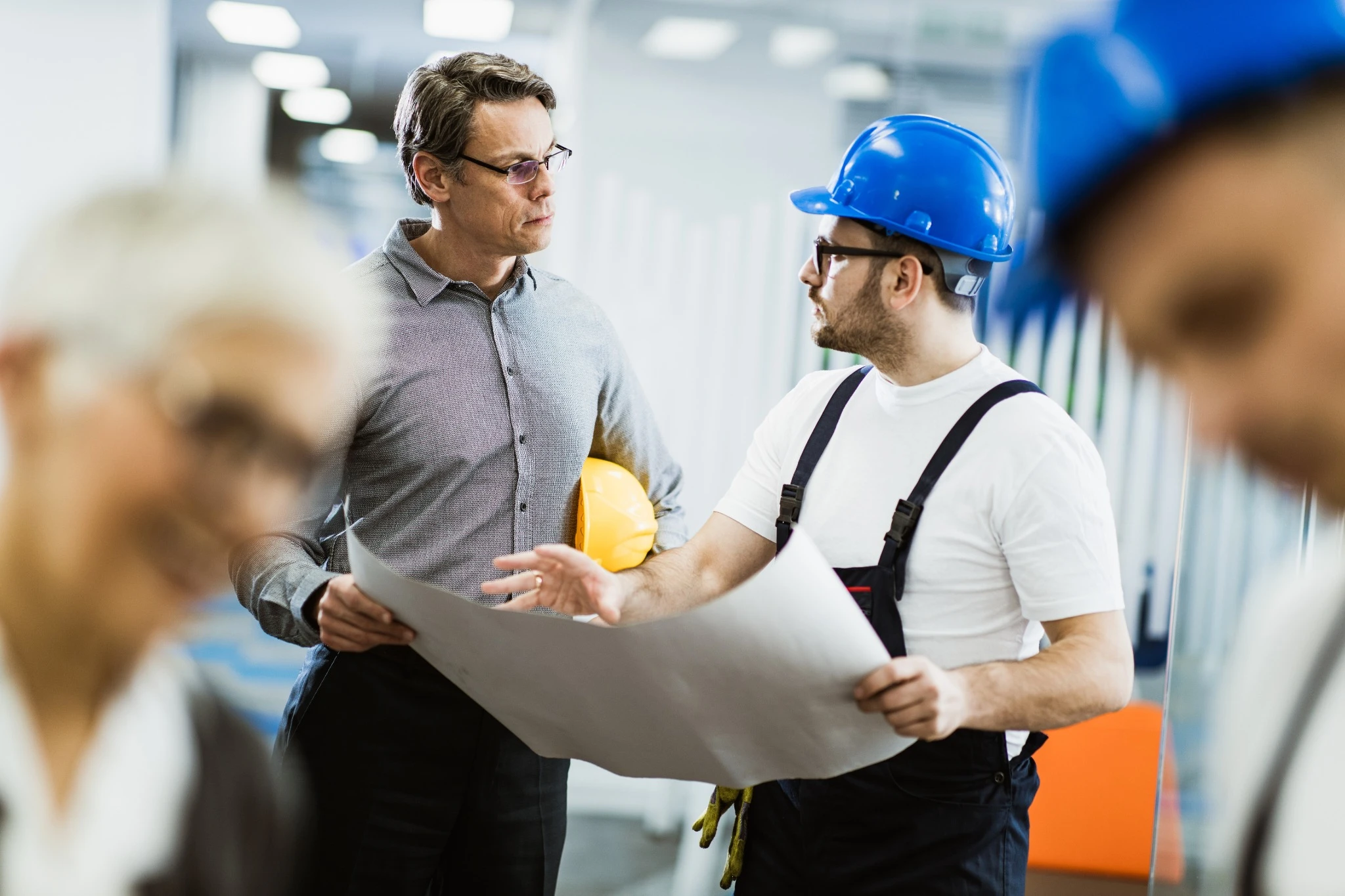 Medarbetare i industriell miljö diskuterar ritning som del av förhandlingsträning hos Ahlsell.